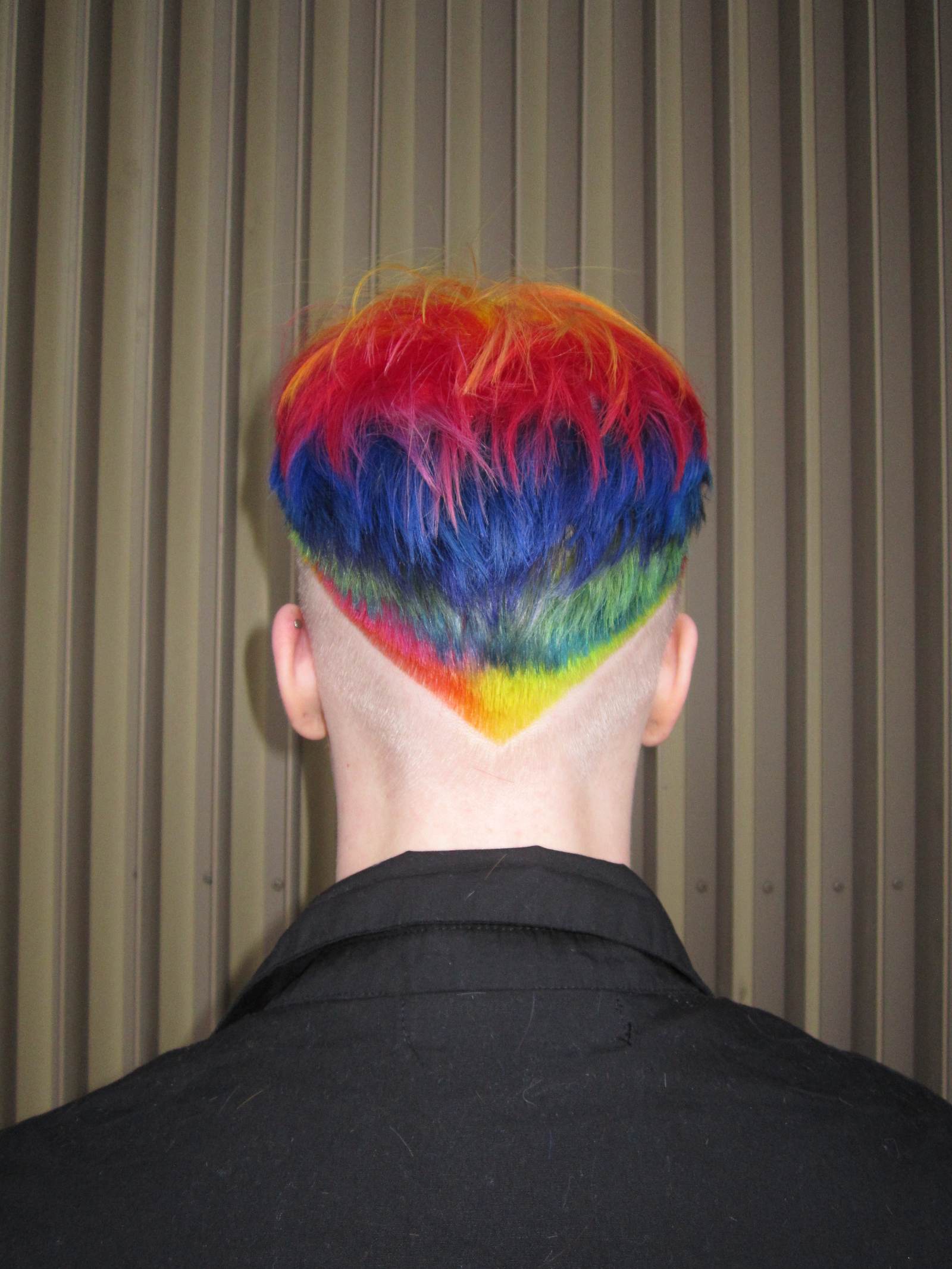 Vivid rainbow hair transformation at Assort Melbourne featuring saturated layers of purple, green, and orange with a high-shine "glass hair" finish.