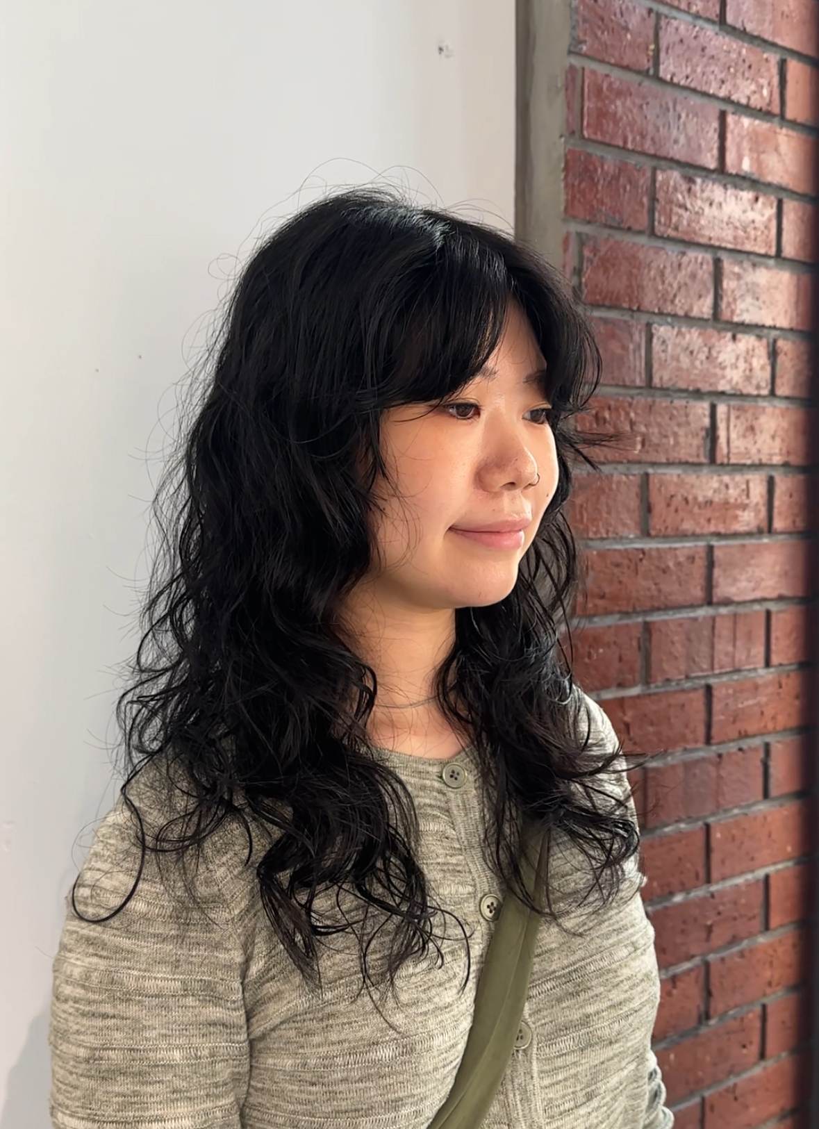 A client at Assort Melbourne salon showcasing frizz-free, voluminous curly hair with soft layers, demonstrating professional curly hair maintenance.