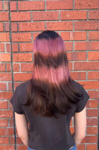 Back of the head of a vibrant pink "Angel Halo" face-framing hair trend on long dark hair at Assort Melbourne.