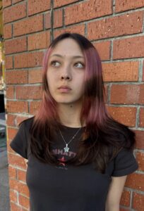 Close-up of a vibrant pink "Angel Halo" face-framing hair trend on long dark hair at Assort Melbourne.