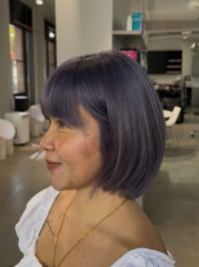 Stylist at Assort Melbourne finishing a sharp Executive Bob with a high-shine blowout.
