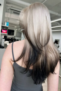 A seamless light-to-dark gradient hair color at Assort Melbourne, featuring creamy blonde roots transitioning into deep charcoal tips with a high-shine finish.