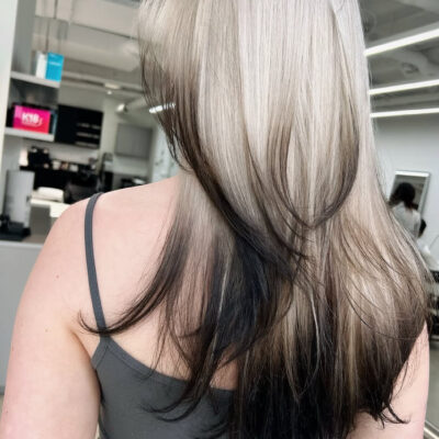 A seamless light-to-dark gradient hair color at Assort Melbourne, featuring creamy blonde roots transitioning into deep charcoal tips with a high-shine finish.