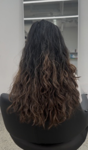Long dark wavy hair with faded colored ends before a big haircut transformation at Assort Melbourne.