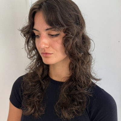 A client at Assort Melbourne salon showcasing frizz-free, voluminous curly hair with soft layers, demonstrating professional curly hair maintenance.