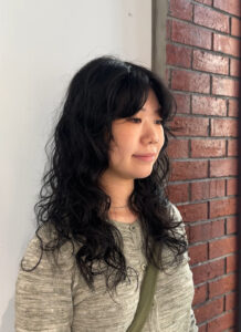 A client at Assort Melbourne salon showcasing frizz-free, voluminous curly hair with soft layers, demonstrating professional curly hair maintenance.