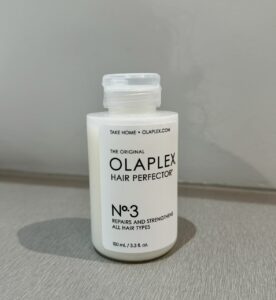 A bottle of Olaplex No. 3 sitting on a salon shelf at Assort Melbourne, recommended for maintaining the strength and shine of Raccoon Streak hair color.