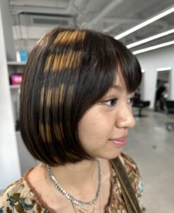 A client at Assort Melbourne showcasing high-contrast black and bleached horizontal Raccoon Streaks on a modern layered haircut