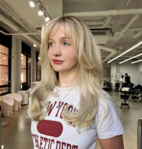 Stylist at Assort Melbourne finishing a sharp Butterfly cut with a high-shine blowout.