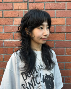 client at Assort Melbourne showcasing a long, layered haircut with face-framing movement and a high-shine finish using Evo products