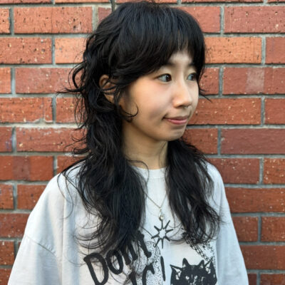 client at Assort Melbourne showcasing a long, layered haircut with face-framing movement and a high-shine finish using Evo products