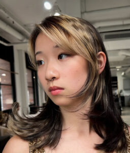 A client at Assort Melbourne showcasing high-contrast platinum horizontal Raccoon Streaks on a modern layered haircut