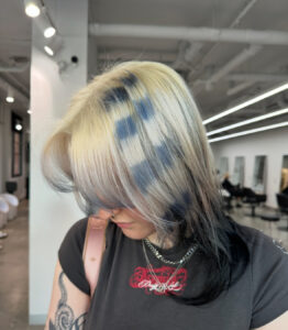 A client at Assort Melbourne showcasing high-contrast Navy horizontal Raccoon Streaks on a bright blonde hair with a modern layered haircut