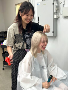Behind the Scenes photo of Assort Melbourne stylist teaching client how to style bangs for a social media video