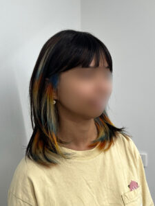 Close-up of "Light Reflection" hair technique featuring vibrant blue and orange creative color.