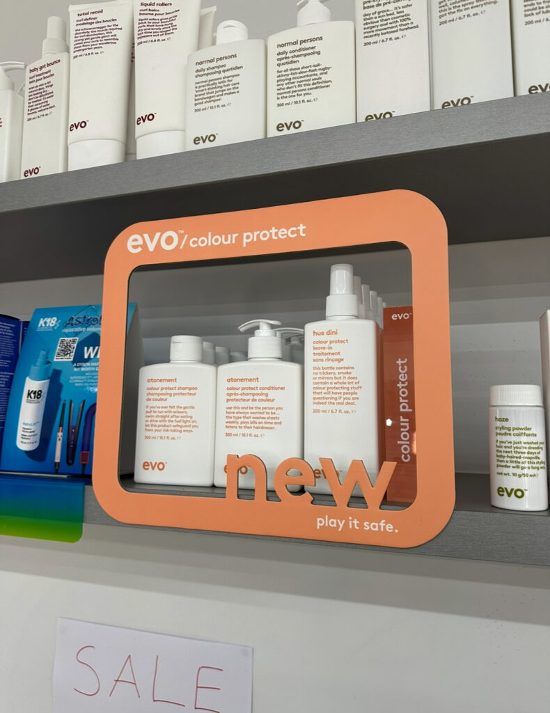 Evo Atonement Colour Protect Shampoo, Conditioner, and Hue Dini Leave-in bottles on a minimalist salon shelf at Assort Melbourne.