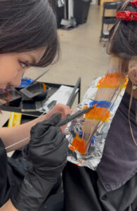Close-up of "Light Reflection" hair technique featuring vibrant blue and orange creative color.